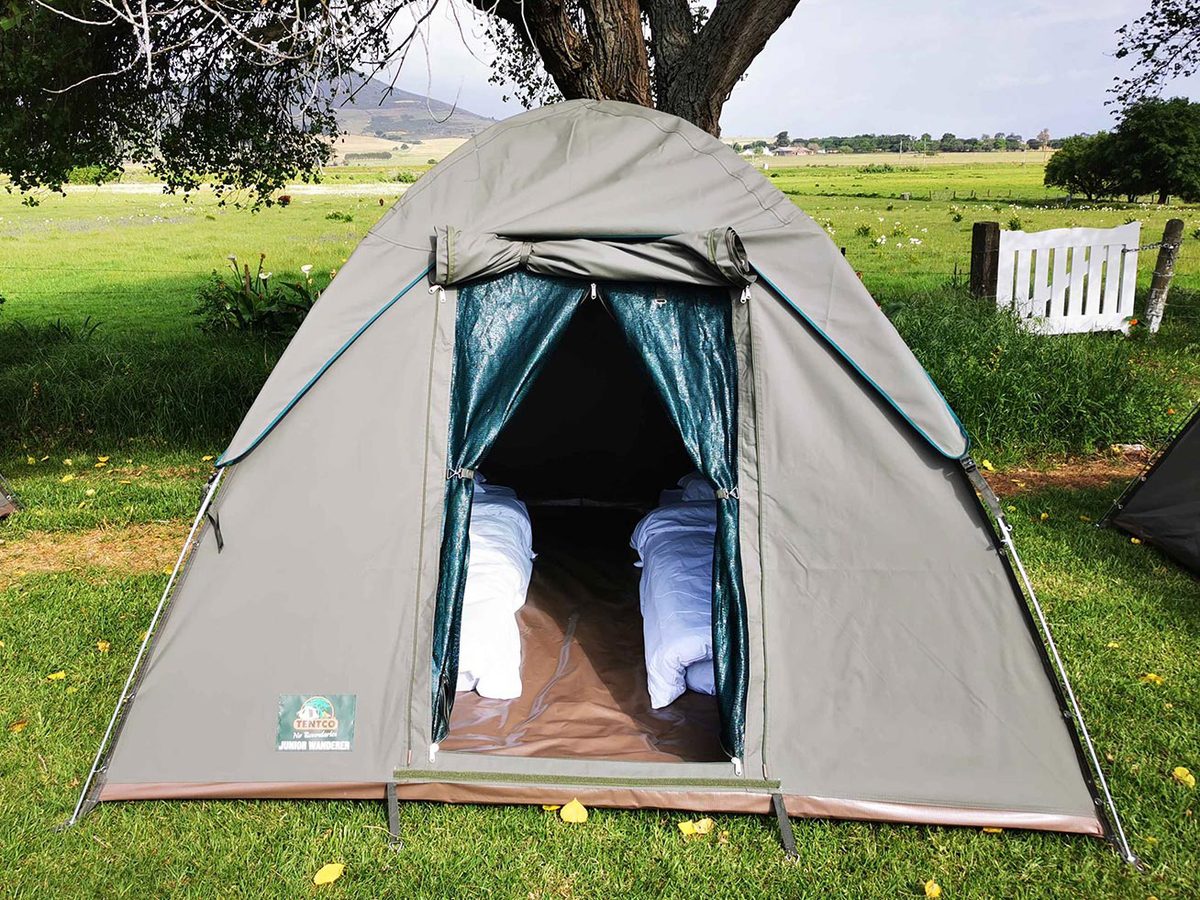 A pitched canvas tent with two made-up beds inside