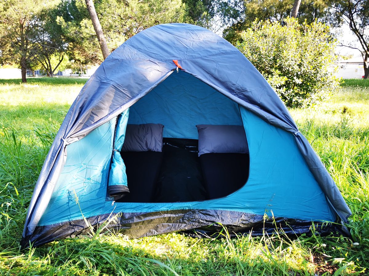 A pitched nylon dome tent with two made-up mattresses inside