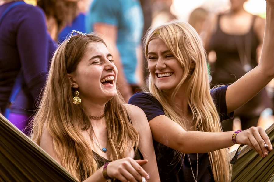 Two friends laughing together in a hammock beside the dance floor
