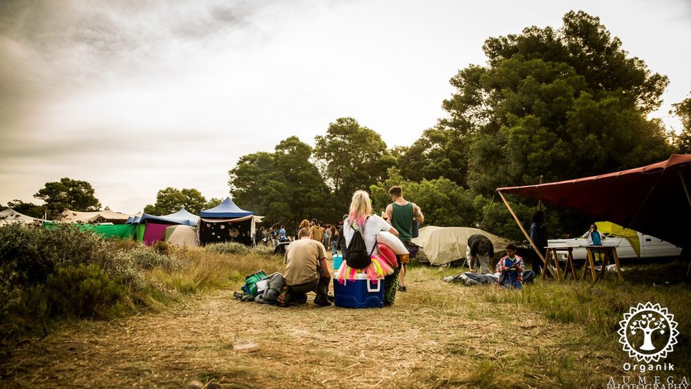Festival-goers setting up camp among the tents as the sun goes down